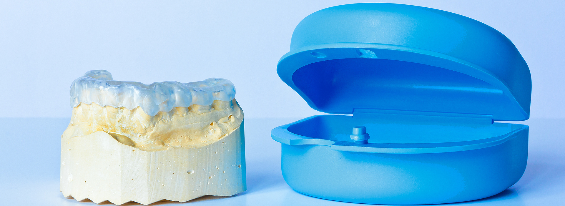 The image shows two dental implants one with a blue cap and another without any cap, placed on a plain white background.